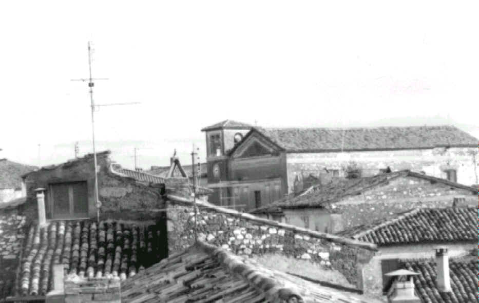 Foto in bianco e nero. Si vedono i tetti del paese con in fondo il tetto della chiesa seguito dalla cima del campanile.