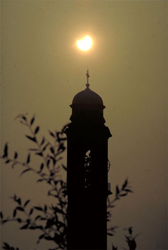 Un' eclisse di sole adombra il campanile della parrocchiale.